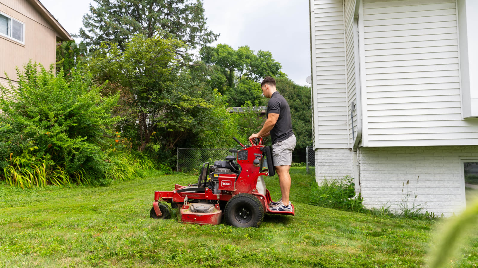 Heartland Grounds crew member mowing a residential Iowa lawn with a stand-on mower