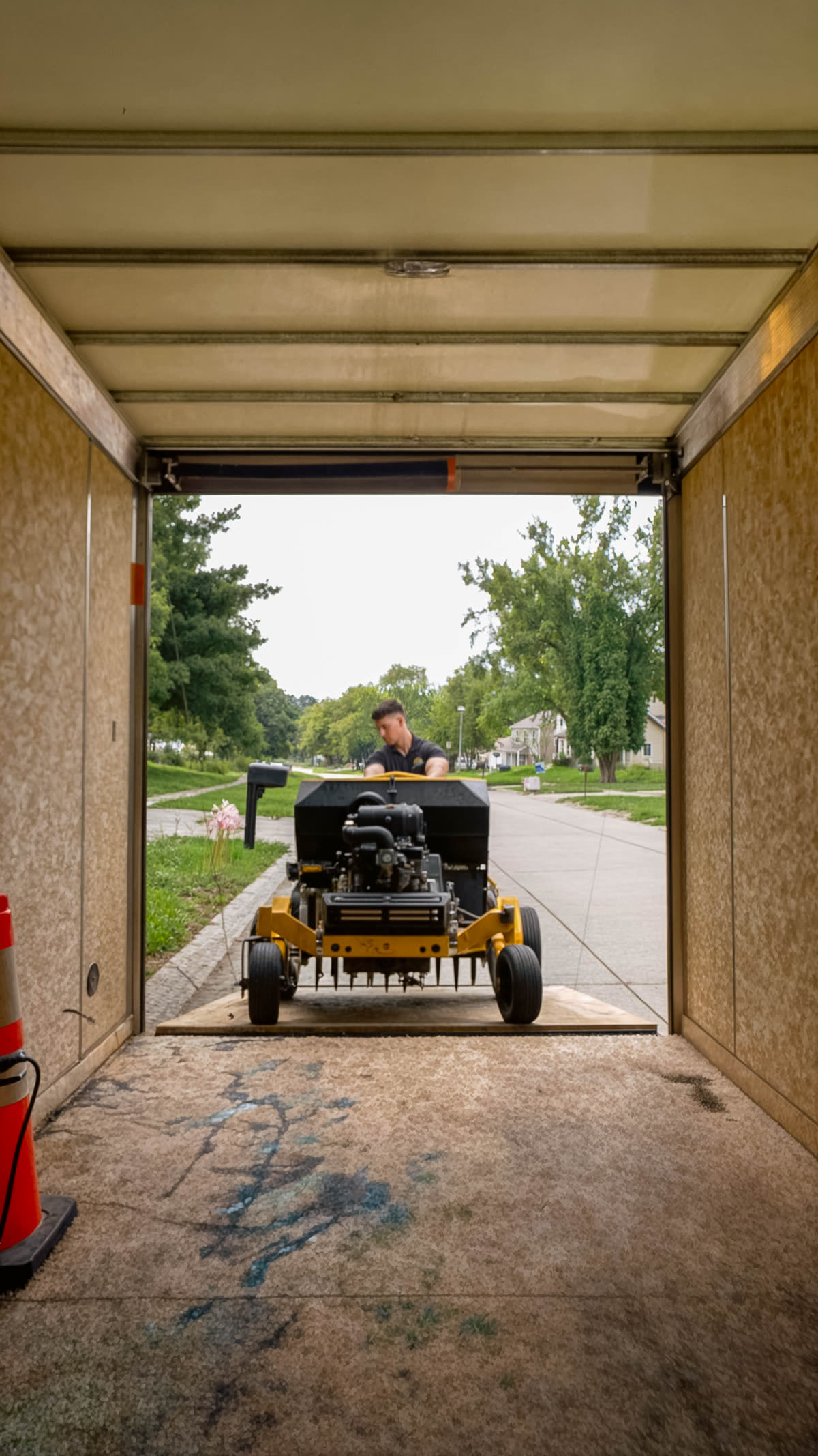 Heartland Grounds crew member unloading a commercial core aerator from the trailer on a Coralville street