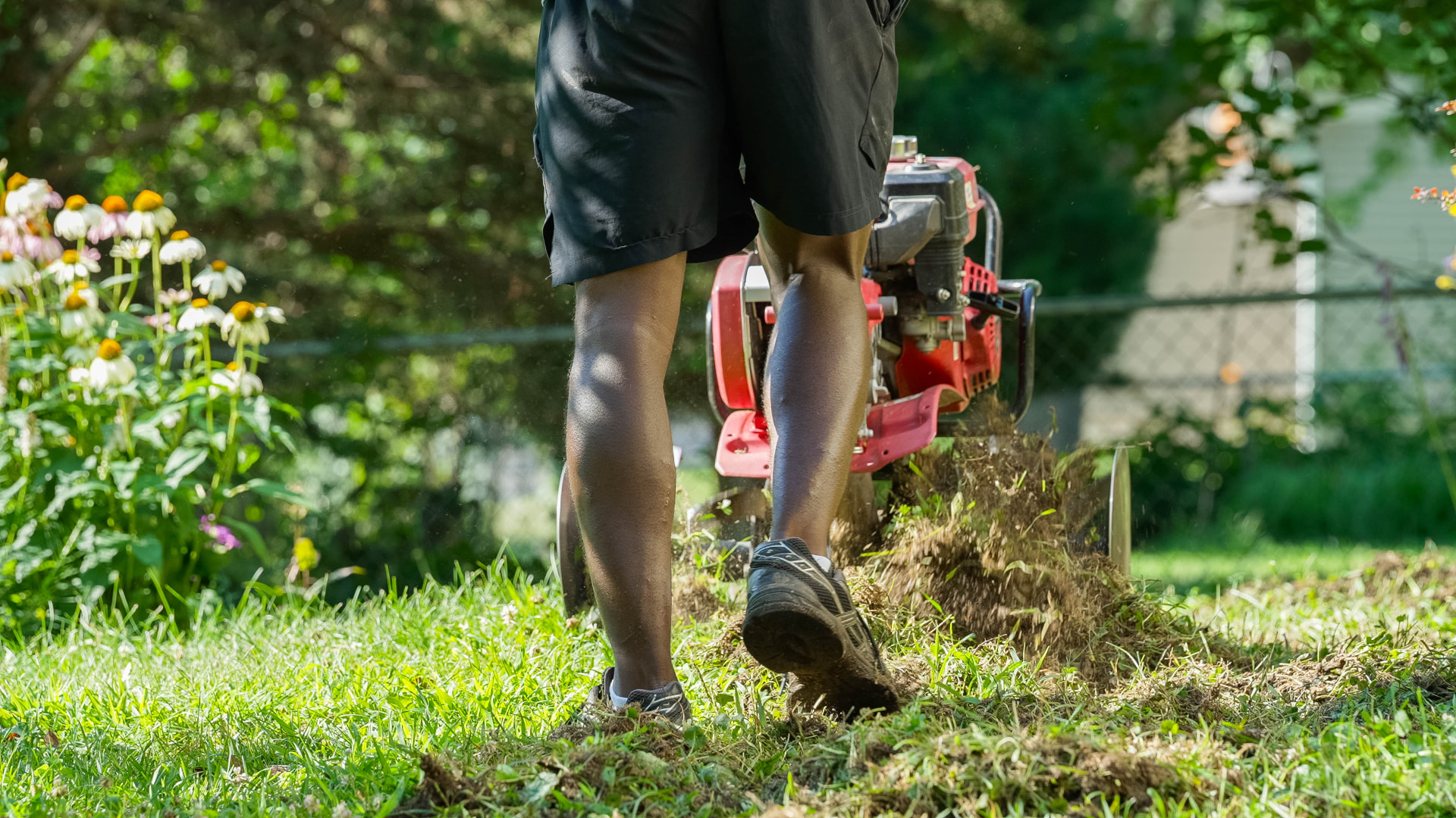 Heartland Grounds crew member running a core aerator across an Iowa lawn, pulling soil plugs to the surface